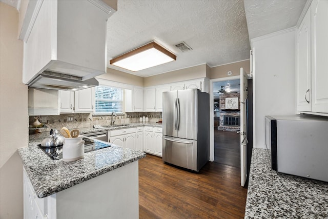 kitchen featuring custom exhaust hood, stainless steel refrigerator, stone counters, white cabinets, and sink