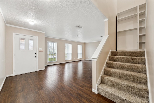 entryway featuring dark wood-type flooring, a textured ceiling, and crown molding