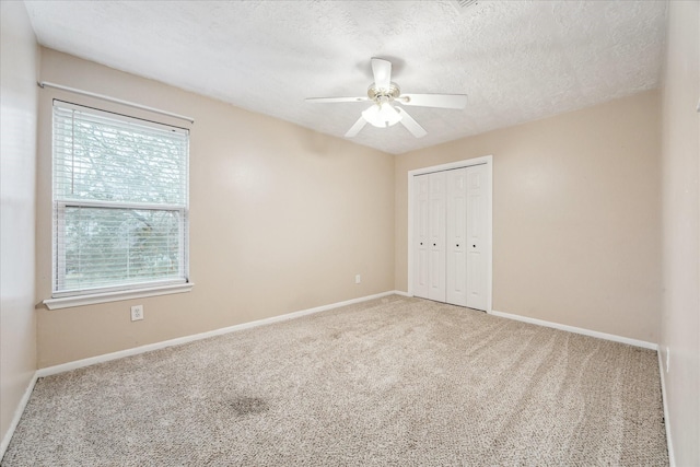 unfurnished bedroom with a textured ceiling, ceiling fan, a closet, and carpet