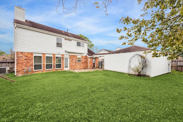 rear view of property featuring a yard, central AC, and a patio area