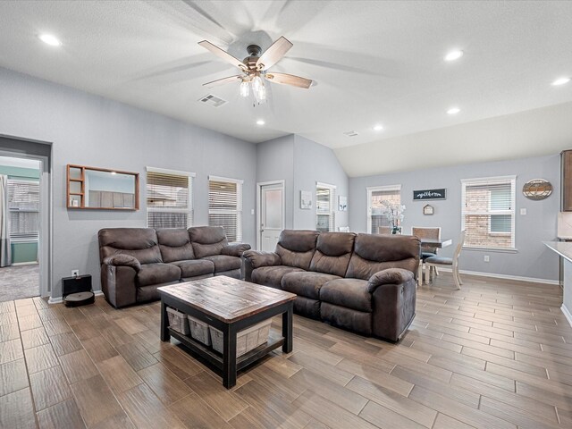 living area with vaulted ceiling, ceiling fan, visible vents, and wood tiled floor