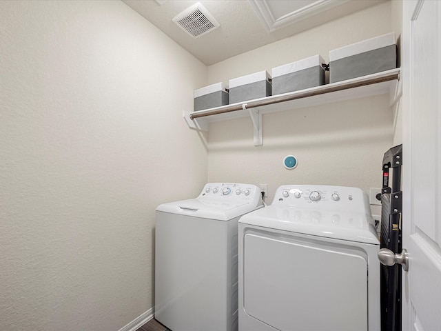 laundry area featuring laundry area, visible vents, separate washer and dryer, and a textured wall