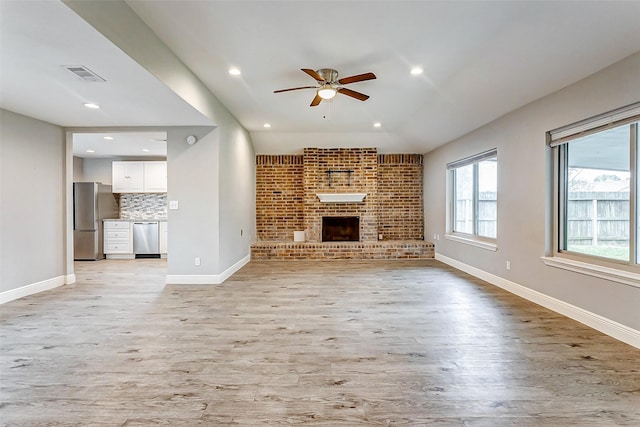 unfurnished living room featuring a brick fireplace, light wood-type flooring, and ceiling fan