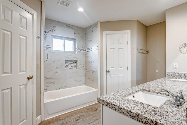 bathroom with tiled shower / bath combo, wood-type flooring, and vanity