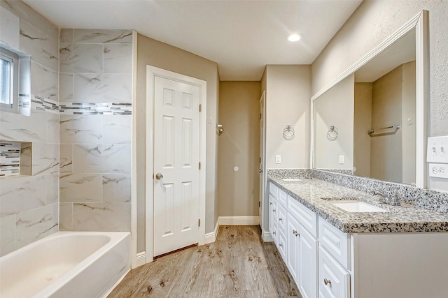 bathroom featuring hardwood / wood-style flooring, tiled shower / bath combo, and vanity