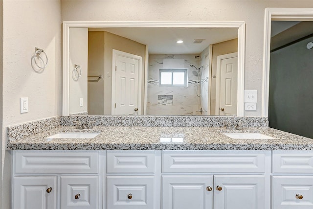 bathroom featuring tiled shower and vanity