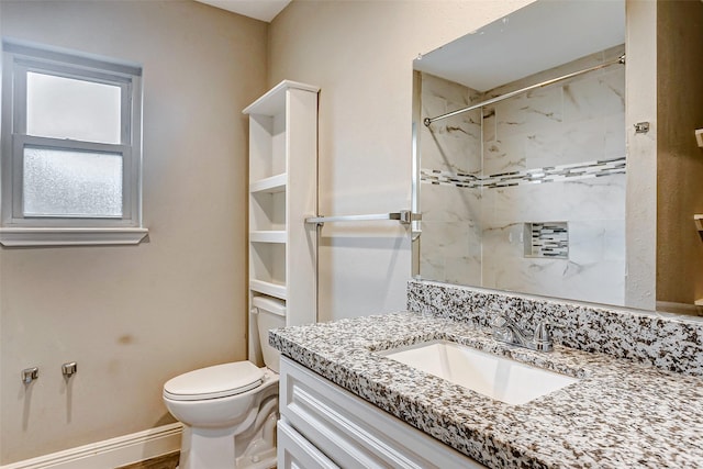 bathroom with toilet, a tile shower, and vanity