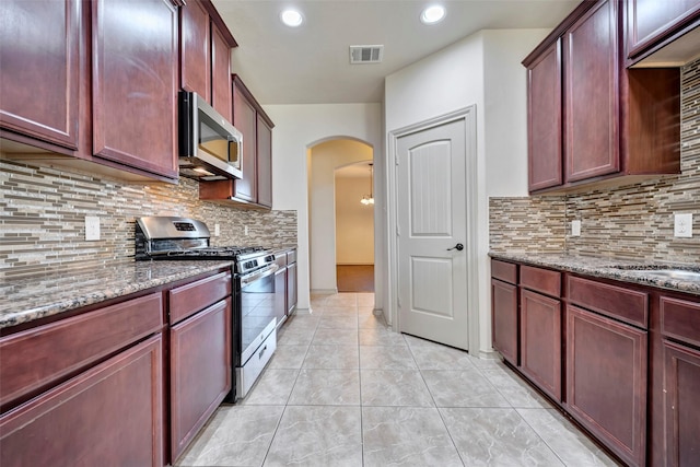 kitchen with stainless steel appliances, light stone counters, decorative backsplash, and light tile patterned floors