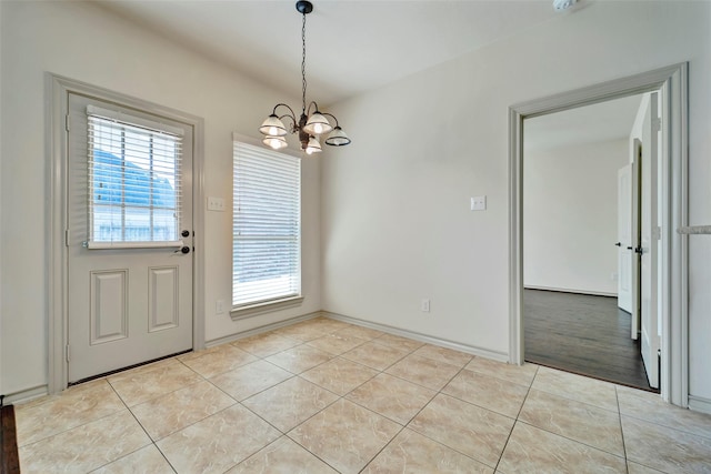 unfurnished dining area featuring an inviting chandelier, light tile patterned floors, and a wealth of natural light