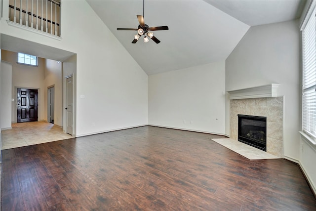 unfurnished living room with hardwood / wood-style flooring, high vaulted ceiling, ceiling fan, and a tile fireplace