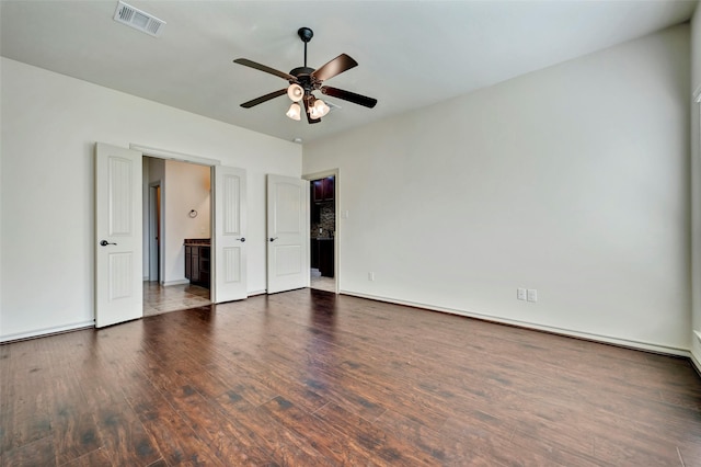 unfurnished bedroom featuring connected bathroom, ceiling fan, and dark hardwood / wood-style floors