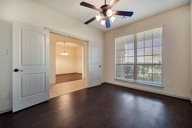 unfurnished room with ceiling fan with notable chandelier and wood-type flooring