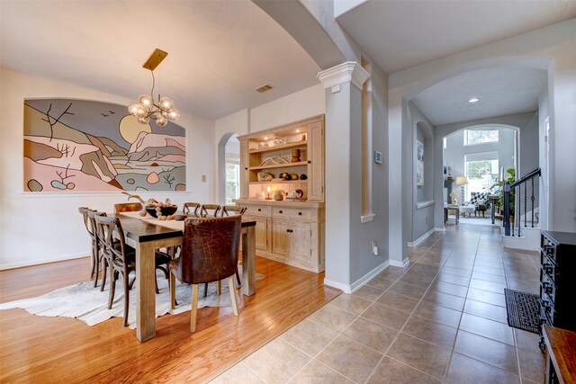 dining area featuring built in shelves, tile patterned flooring, decorative columns, and an inviting chandelier