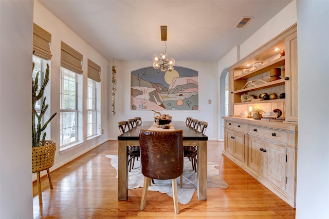 dining area with light hardwood / wood-style floors and a chandelier