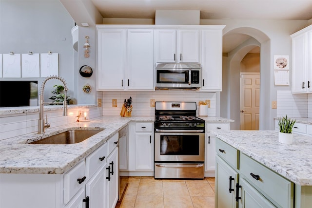 kitchen with sink, white cabinets, backsplash, and appliances with stainless steel finishes