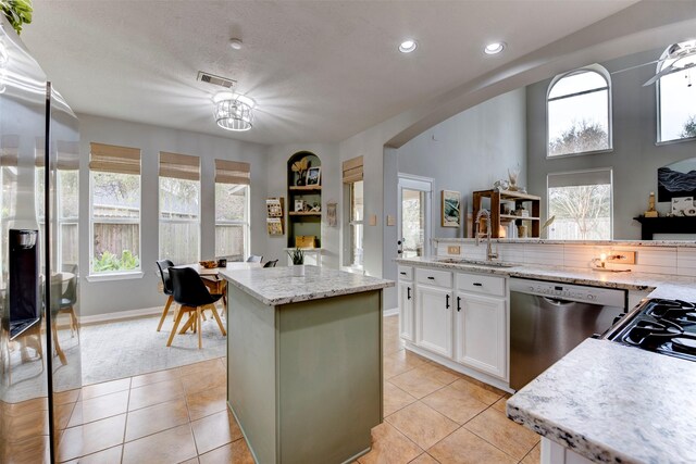 kitchen with dishwasher, a center island, light tile patterned floors, white cabinetry, and sink