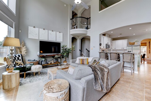 tiled living room featuring a high ceiling, ceiling fan, and a wealth of natural light