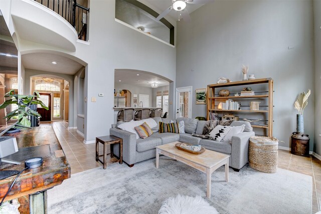 living room featuring ceiling fan, a towering ceiling, and light tile patterned floors