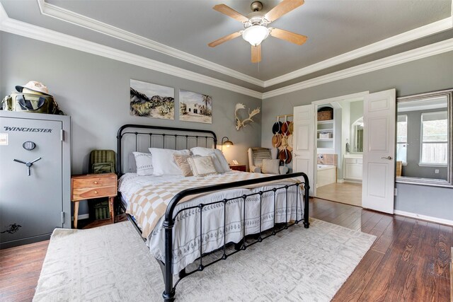 bedroom featuring ceiling fan, ornamental molding, wood-type flooring, ensuite bath, and a tray ceiling