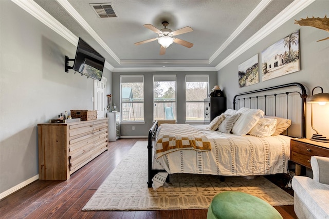 bedroom with dark wood-type flooring, ceiling fan, a tray ceiling, and ornamental molding