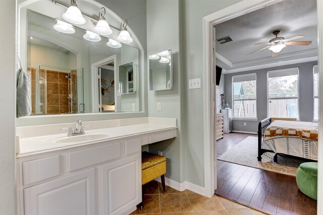 bathroom featuring tile patterned flooring, a shower with door, crown molding, ceiling fan, and vanity