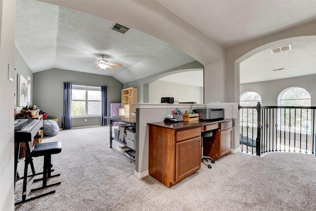 carpeted home office featuring lofted ceiling, a textured ceiling, and ceiling fan