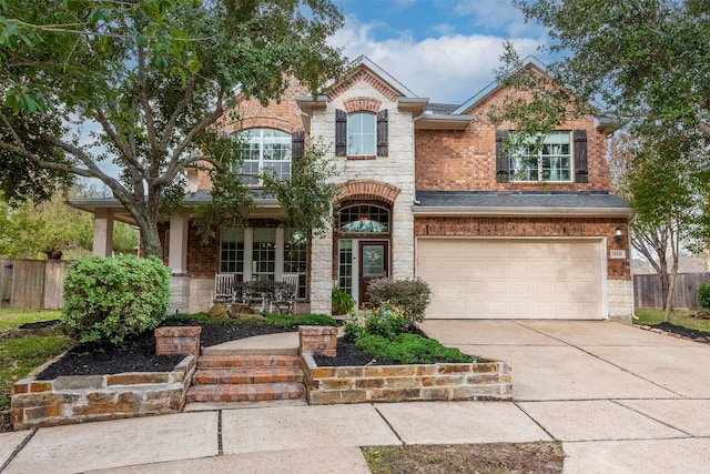 view of front facade with stone siding, concrete driveway, and fence