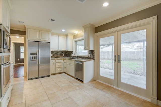 kitchen with stainless steel appliances, french doors, light tile patterned floors, ornamental molding, and sink