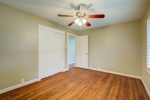 unfurnished bedroom with ceiling fan, a closet, and hardwood / wood-style flooring