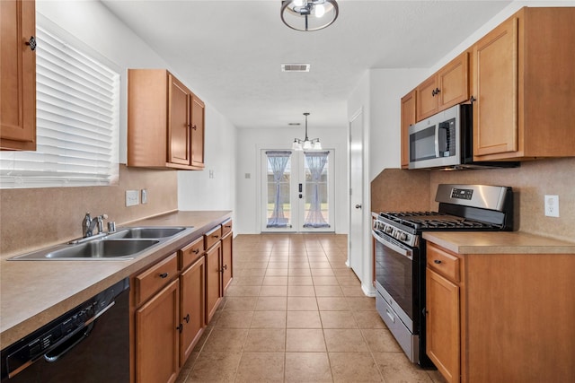 kitchen featuring appliances with stainless steel finishes, pendant lighting, sink, an inviting chandelier, and light tile patterned flooring