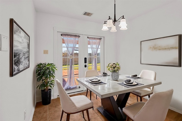 dining area with french doors and a chandelier