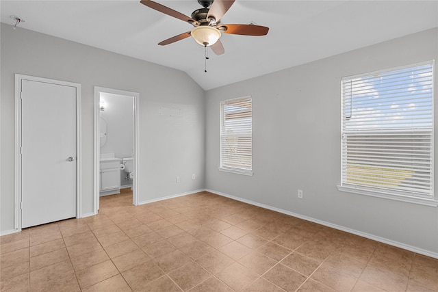 unfurnished bedroom with ceiling fan, multiple windows, ensuite bathroom, and lofted ceiling