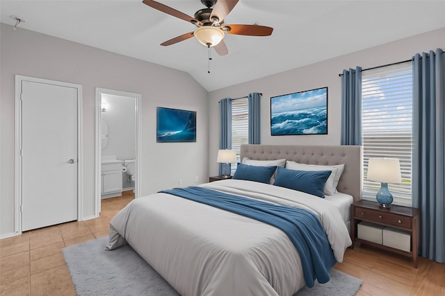 bedroom with lofted ceiling, ceiling fan, light tile patterned floors, and connected bathroom