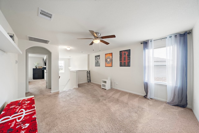 empty room with ceiling fan, a wealth of natural light, and carpet