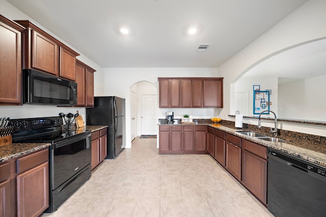 kitchen featuring black appliances, dark stone counters, kitchen peninsula, and sink