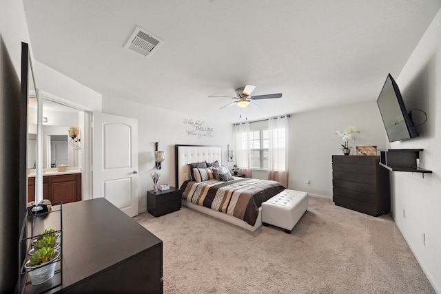 carpeted bedroom with ensuite bath and ceiling fan