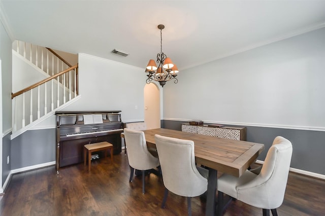 dining area with dark wood-type flooring, crown molding, and a chandelier