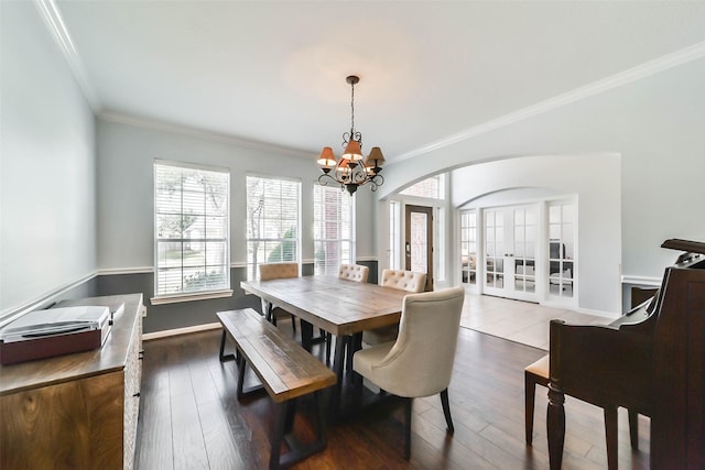 dining space featuring dark wood-type flooring, french doors, crown molding, and a chandelier