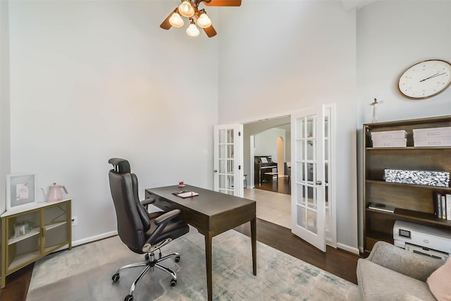 office space with a high ceiling, ceiling fan, french doors, and wood-type flooring