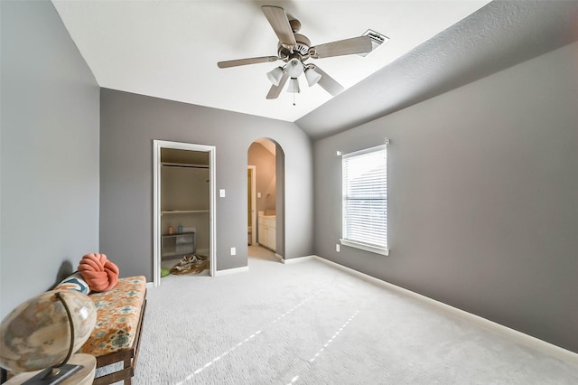 bedroom with lofted ceiling, ensuite bathroom, ceiling fan, and light carpet