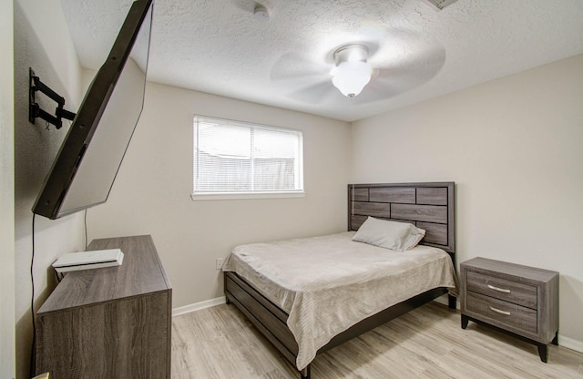 bedroom with a textured ceiling, ceiling fan, and light hardwood / wood-style flooring