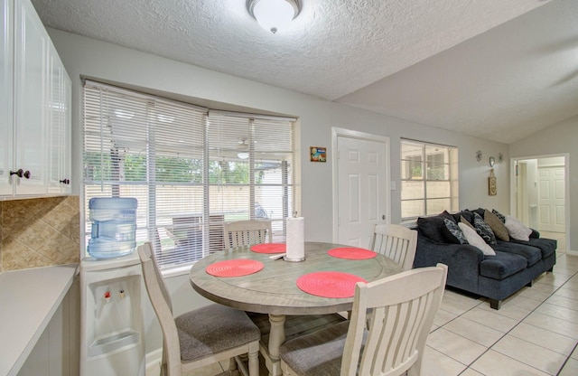 tiled dining space with a textured ceiling and lofted ceiling