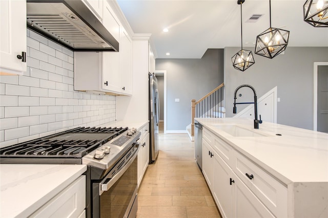 kitchen with light stone counters, pendant lighting, stainless steel appliances, white cabinetry, and ventilation hood