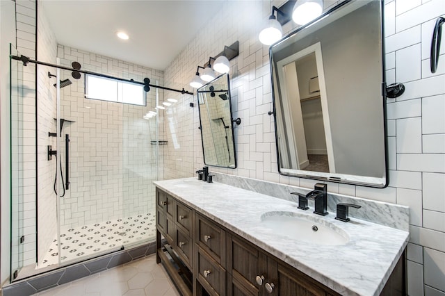 bathroom with vanity, tile patterned flooring, tile walls, and walk in shower