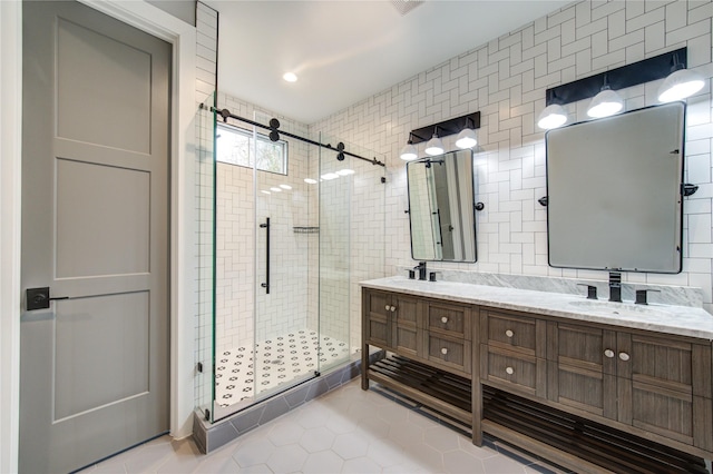 bathroom with tile patterned flooring, tile walls, backsplash, a shower with door, and vanity