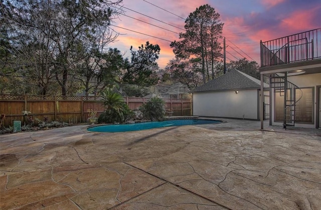 pool at dusk with a patio area