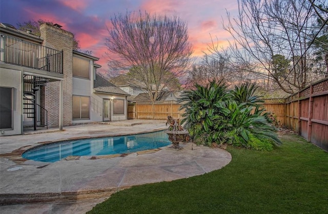 pool at dusk featuring a patio area and a lawn