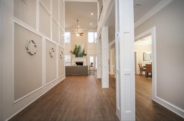 hallway featuring a towering ceiling, crown molding, and dark hardwood / wood-style floors