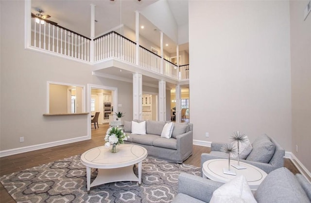 living room with a high ceiling, hardwood / wood-style floors, ceiling fan, and decorative columns