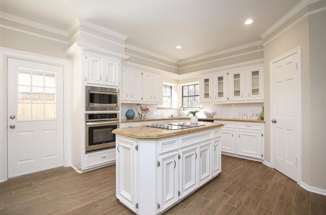 kitchen featuring a center island, stainless steel appliances, tasteful backsplash, hardwood / wood-style floors, and white cabinets